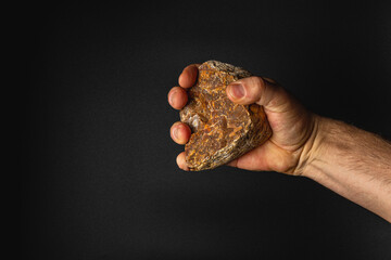 Hand holding a rock against a dark background © mykhailo