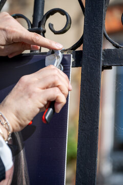mains d'une femme installant un panneau avec des rilsans et une pince coupante sur une cloture, bricolage en ext&eacute;rieur