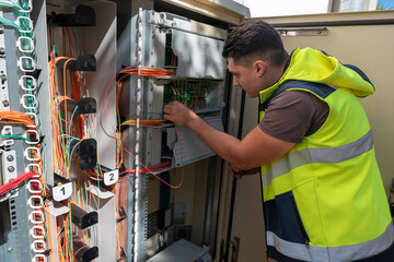 Técnico a fazer manutenção num armário de fibra ótica para garantir a qualidade rede aos...