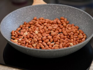 Peanuts in a frying pan being cooked on a black induction hob