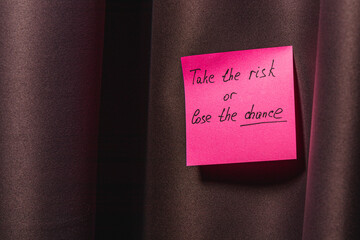 Motivational note says take the risk or lose the chance on a curtain