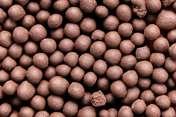 Macro Shot of Chocolate Flavored Cereal Puffs. Top View of Wooden Match Head Tips. Textured Chocolate Snack Balls