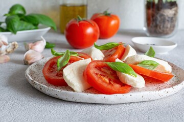 Caprese salad with juicy tomatoes, fresh mozzarella and pesto. Concept for a tasty and healthy appetizer, flat lay. Italian food, cuisine.