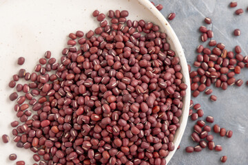 Plate full of dried red azuki beans on gray top view. East Asian legumes, vegetarian protein source