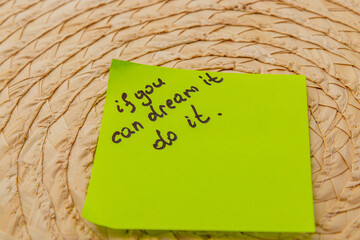 Inspiration note on bright sticky pad placed on woven surface in cozy setting