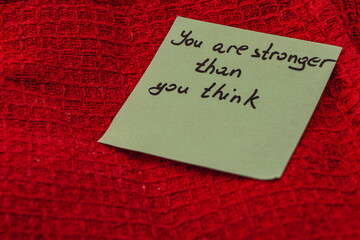 Message of encouragement on a note placed on a red textured surface