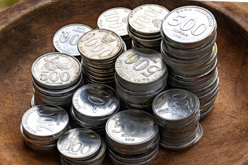 Stacks of Indonesian Rupiah Coins in a Wooden Bowl. Close-Up of 500, 1000, and 200 Rupiah Coins