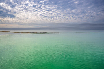 A quiet moment on the coast, a white sandy beach with emerald-green waters of Destin Harbor, with a lifeguard stand standing watch beneath the open sky, ready for sunny days and salty breezes.