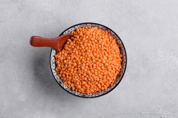 Organic red lentils in a ceramic bowl on gray table background, pulses for healthy balanced diet,...