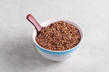 Raw lentils in ceramic bowl on a light gray table, selective focus. Legume for healthy balanced diet, plant-based protein source