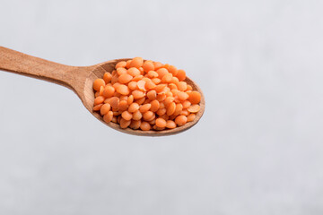 Organic red lentil on wooden spoon, close up texture, legumes for vegan and vegetarian cooking,...