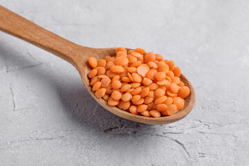 Organic red lentil on wooden spoon, close up texture, legumes for vegan and vegetarian cooking,...