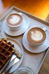 Delicious Breakfast with Two Cups of Latte and Waffles on a Tray in Natural Light
