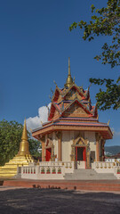 Fototapeta premium Beautiful Buddhist temple. The roof of the pagoda features triangular cornices, gilded ornaments, and decorative sculptures. A stupa and a spire against the blue sky. Malaysia. Penang. Georgetown