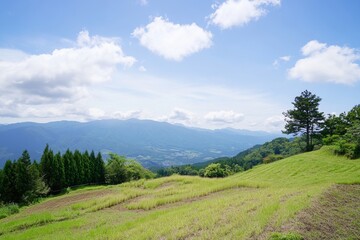 Obraz premium Landscape view with green hills and mountains under a bright, blue sky