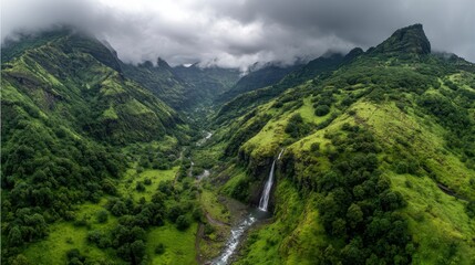 Majestic Mountain Vista: An awe-inspiring landscape unfolds, a verdant valley and cascading waterfall nestled between imposing peaks. The sky is overcast.