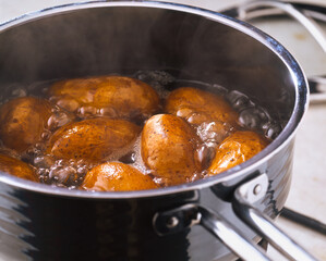 Boiling potatoes in a pot on the stove in a kitchen setting