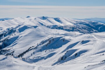 Fototapeta premium Snowy mountains under a clear sky create a beautiful, winter landscape