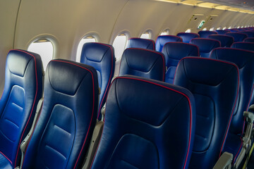 Fototapeta premium Rows of empty blue leather seats with three seats in the cabin of a cheap airline