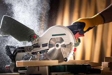 Close-up of a carpenter using a circular saw to cut  board