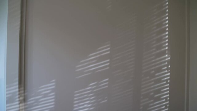 Light through the blinds, shadows on the wall, the pattern of the blinds.