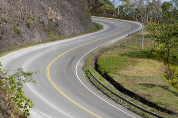 Winding road curves through lush greenery in a mountainous area under bright daylight. Dominican Republic.