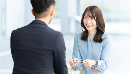 名刺交換をする男女2人のビジネスマン