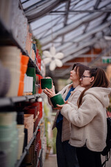 Women Choosing Ceramic Planters in Garden Store Aisle