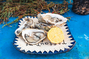 Fresh Oysters with Lemon on Traditional Moroccan Ceramic Plate on blue table, coastal cuisine from Essaouira Port, Morocco