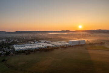 Sunrise drone aerial view, with a factory near a german village in a rural scenery