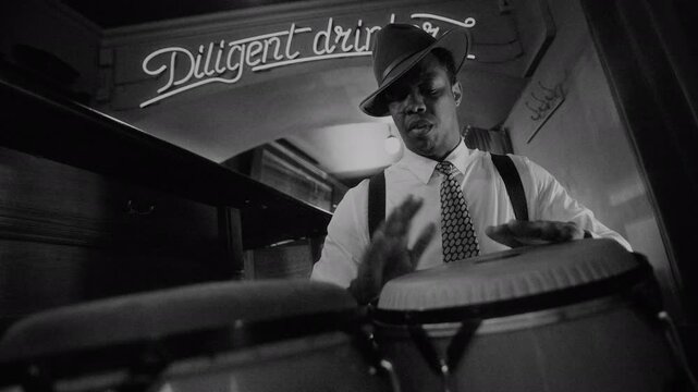Black and white shot of African American man in suspenders and tilted fedora passionately playing congas beneath glowing neon sign, embodying soul of vintage jazz
