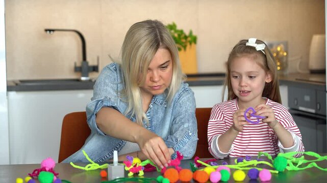 Happy family fun create handmade craft. Mother and little daughter make together diy from colored chenille wire toys. Leisure with children