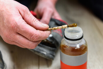 Hands gluing together torn used shoes in home.