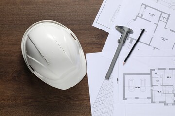 Different architectural drawings, hard hat, pencil and vernier caliper on wooden table, flat lay