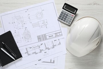 Different engineering drawings, hard hat, pen, divider and calculator on light wooden table, flat...