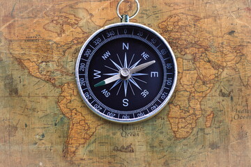 Classic round compass on background of old vintage map of world