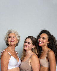 Three women of different ages and backgrounds stand together in their underwear, smiling and radiating confidence. The image promotes diversity, body positivity and self-acceptance