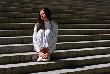 Gen Z woman enjoying a beautiful day in May on the concrete stairs of a park in Stuttgart