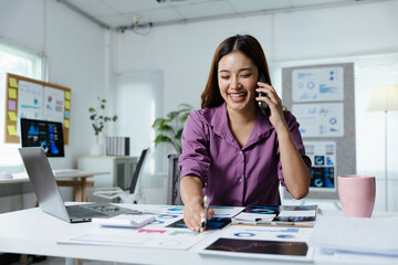 Fototapeta premium Businesswoman is talking to clients and colleague on the phone and working on tablet in the office