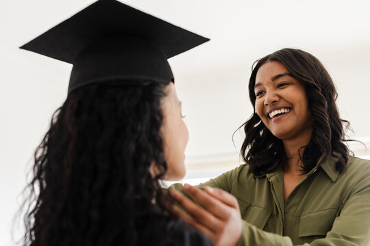 Proud mother celebrating daughter's graduation at home, both smiling joyfully
