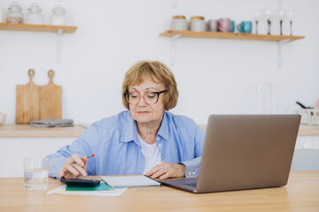 Senior business woman holding paper bill using calculator, old lady managing account finance,...
