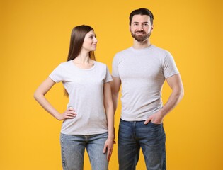 Fototapeta premium Woman and man wearing blank white t-shirts on orange background. Mockup for design