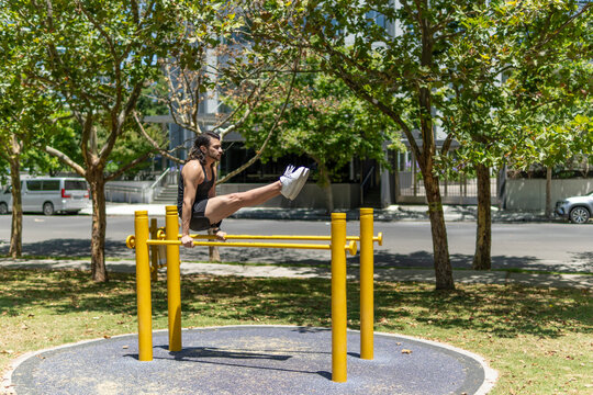 Fit sporty man exercising on the parallel bars in a park
