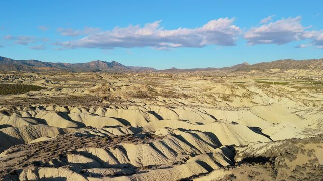 Barren tabernas desert landscape showcasing rugged terrain, rocky outcrops, and drought-resistant vegetation under shifting sunlight in southern spain