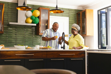 Preparing healthy meal, senior couple in modern kitchen, talking and smiling