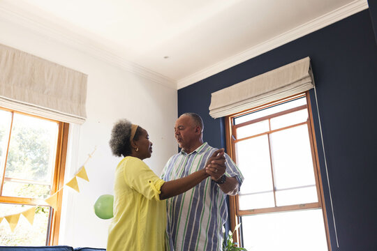 Celebrating birthday, Senior couple dancing joyfully at home, enjoying happy moment together - Powered by Adobe