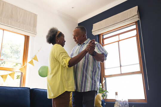 Celebrating birthday, Senior couple dancing joyfully at home, enjoying each other's company - Powered by Adobe