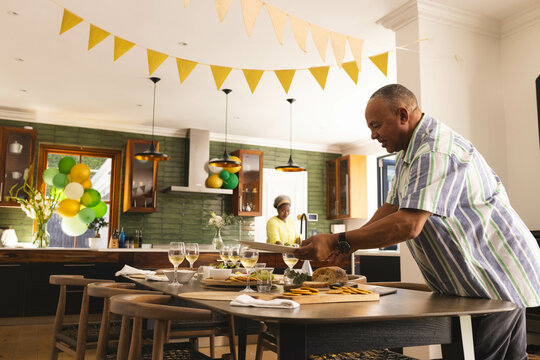 Senior couple preparing festive meal in modern kitchen, setting table with care
