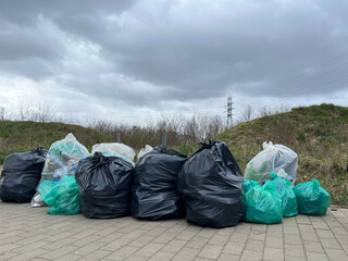 Plastic bags with garbage, collected in a pile. Garbage removal. The result of garbage collection...