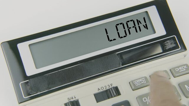"Loan" text or words displayed on a calculator's LED screen as a hand types numbers, symbolizing the process of borrowing money with an agreement to repay it with interest over time